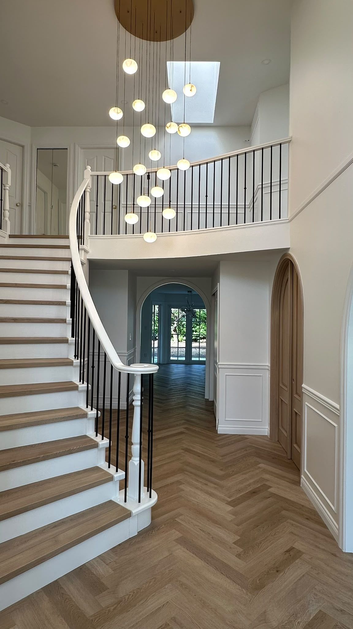 Curved stair, oak flooring and globe pendants at a North Vancouver renovation